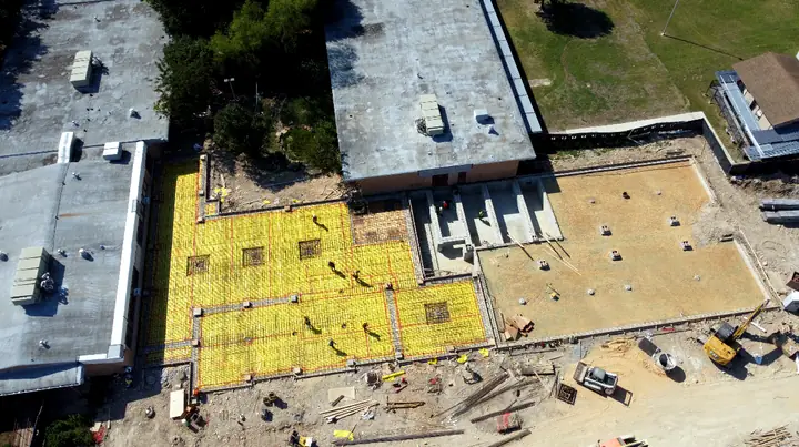 Rebar laid out for new slabs beside an existing building, seen from the air