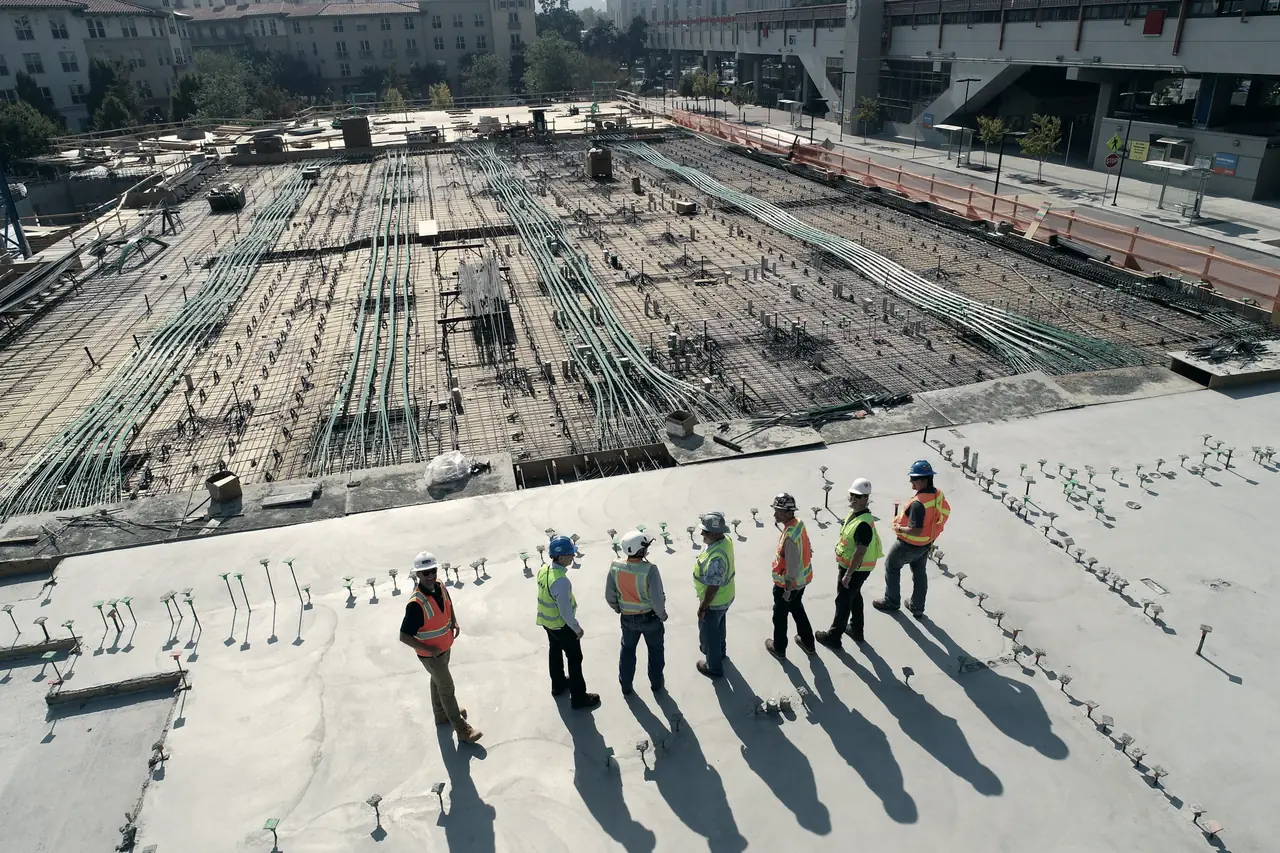A crew in hard hats and high-visibility vests looking over a large rebar mat before the pour